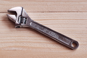 Adjustable wrench on wood background