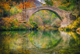 Ancient roman stone bridge Pont des Tuves across the Siagne river surrounded by yellow autumn trees near Saint-Cezaire-sur-Siagne, Alpes Maritimes, France