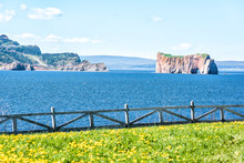 View Of Rocher Perce From Bonaventure Island With Ocean And Gannet Birds Flying, Cityscape Skyline Or Coastline Of City, White Fence And Flowers