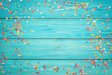 colorful confetti on a wooden turquoise background . free copy space