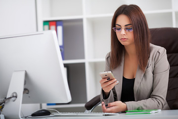 Young business woman working on laptop and talking on mobile phone