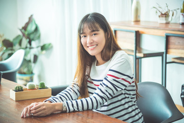 Wall Mural - Beautiful young asian woman sitting at home and smiling at camera