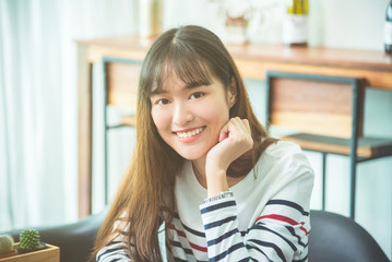 Wall Mural - Beautiful young asian woman sitting at home and smiling at camera