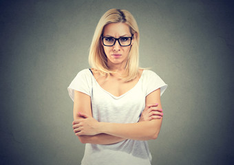 Portrait of an angry woman standing with arms folded on gray background