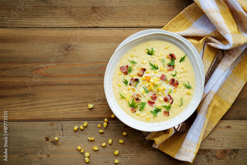 Fotografie, Obraz Corn chowder soup with bacon. Brown wooden background. Top view
