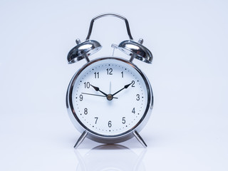 Big old vintage alarm clock with bells on white back ground with shadow reflection on the ground.