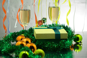 Two glasses of champagne with a gingerbread house New Year's decorations on a New Year's table on a background of a Christmas tree