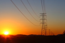 High-power Electric Distribution Tower With The Setting Sun In The Background
