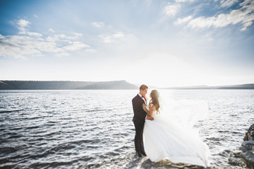 Elegant stylish happy wedding couple, bride, gorgeous groom on the background of sea and sky