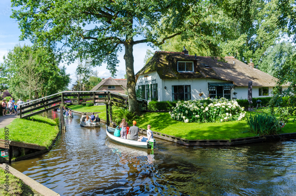     Giethoorn, Netherlands: View of famous Giethoorn village with canals and rustic thatched roof houses.The beautiful houses and gardening city is know as "Venice of the North" - obrazy, fototapety, plakaty 