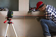 © artursfoto - Handyman drawing a line on dry wall with help of laser leveler