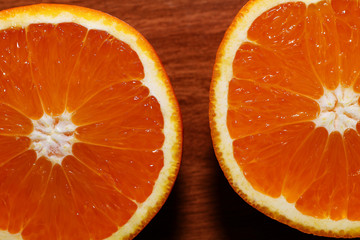 The half-cut orange. Two halves of juicy ripe orange on a wooden table