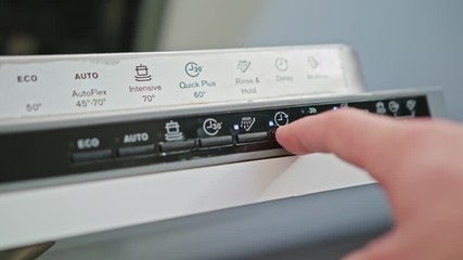 A finger is pushing on the button on off on a dishwasher. Close-up shot