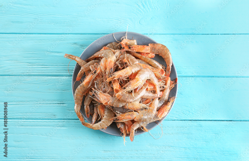 Plate with fresh shrimps on color wooden  background