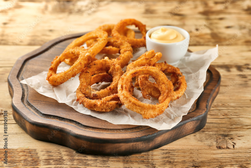 Fried onion rings with sauce on wooden board