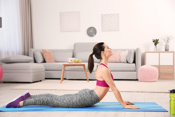 Poster - Young sporty woman doing exercise at home