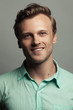 © Augustino - Male beauty, boy next door concept. Portrait of smiling 30-year-old man standing over gray background. Close up. Classic style. Wavy glossy blond hair. Studio shot