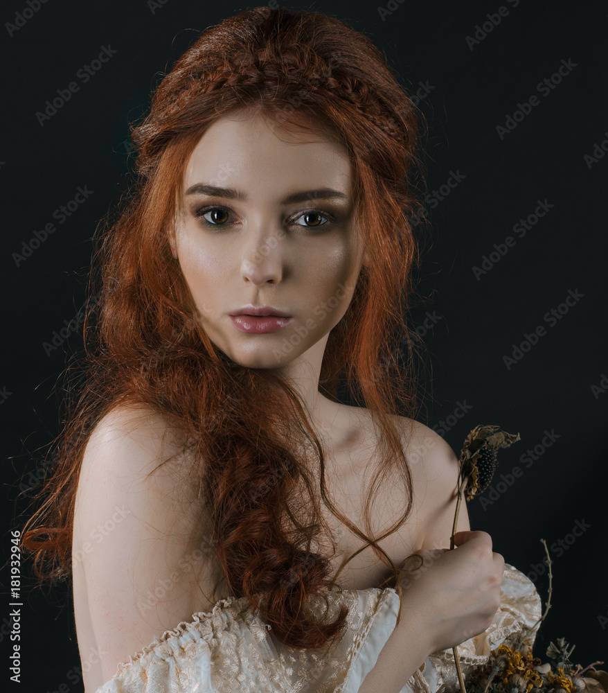 A close-up portrait of a red-haired young woman in a vintage gold dress with