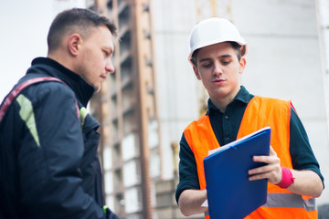 engineer talking discussing with Architect working with blueprints for architectural plan, sketching a project.