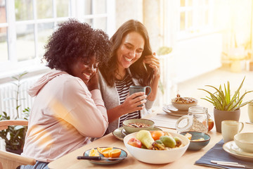 Zwei glückliche Frauen essen Frühstück in Küche