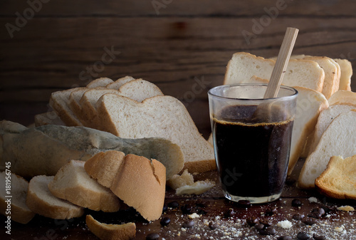 Fotografia, Obraz Rotten breads and rancid coffee on old brown wooden table in dim light room