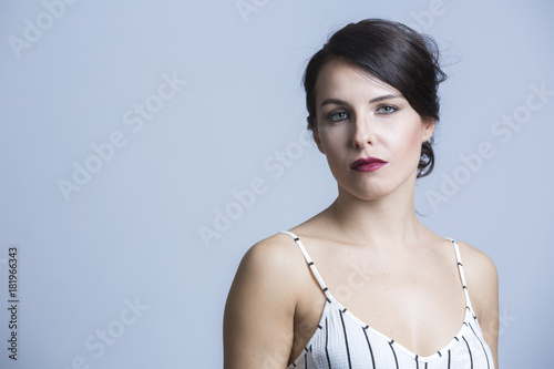 Fotografie, Obraz Ragazza vestita con abito bianco a righe nere con bretelline , ci guarda seria -