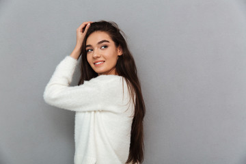 fashionable girl with long hair touching her head, looking aside