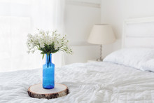 White Flowers In Blue Bottle On Bed