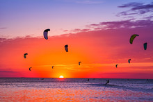 Kite-surfing Against A Beautiful Sunset. Many Silhouettes Of Kites In The Sky. Holidays On Nature. Artistic Picture. Beauty World.