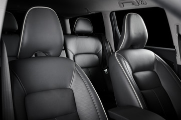 Luxury car inside. Interior of prestige modern car. Comfortable leather seats. Black perforated leather cockpit with isolated black background.