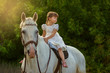 the little girl sits on a horse astride