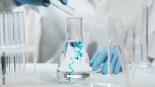 Cuadros en Lienzo Chemist pouring substance into conical flask with liquid, chemical experiment