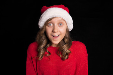 Excited young girl in red sweater and Santa's cap