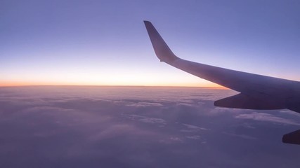 Wall Mural - timelapse of view from window of plane at sunset. flying above clouds.