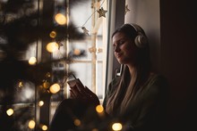 Woman Listening To Music On Mobile Phone During Christmas Eve