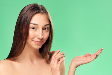 Wall Mural - Beautiful woman shows a blank space on the palm on a green background