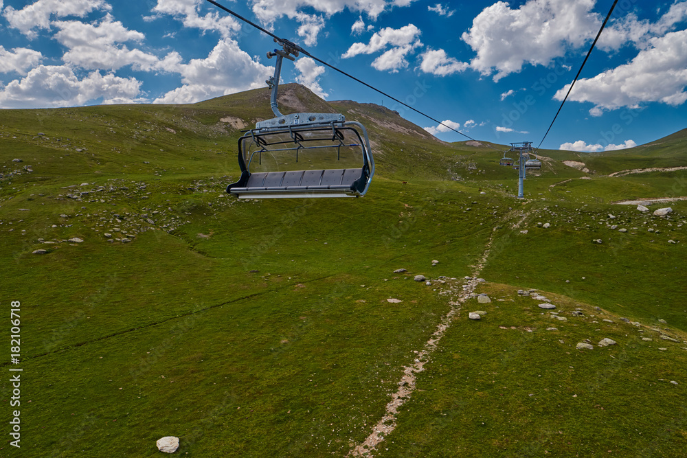 Aerial ropeway high in the mountains of Caucasus with grass plains and ...
