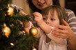 © Martinan - Mother helping her daughter decorate xmas tree