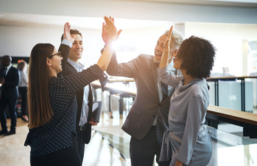 Smiling business colleagues high fiving each other in an office