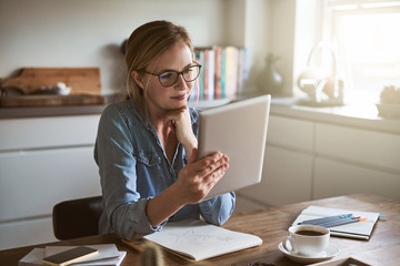 Focused young entrepreneur working online in her kitchen