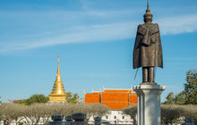 The Bronze Statue Standing In Front Of National Museum Of Nan Province In Thailand With Wat Phra That Chang Kham At The Background.