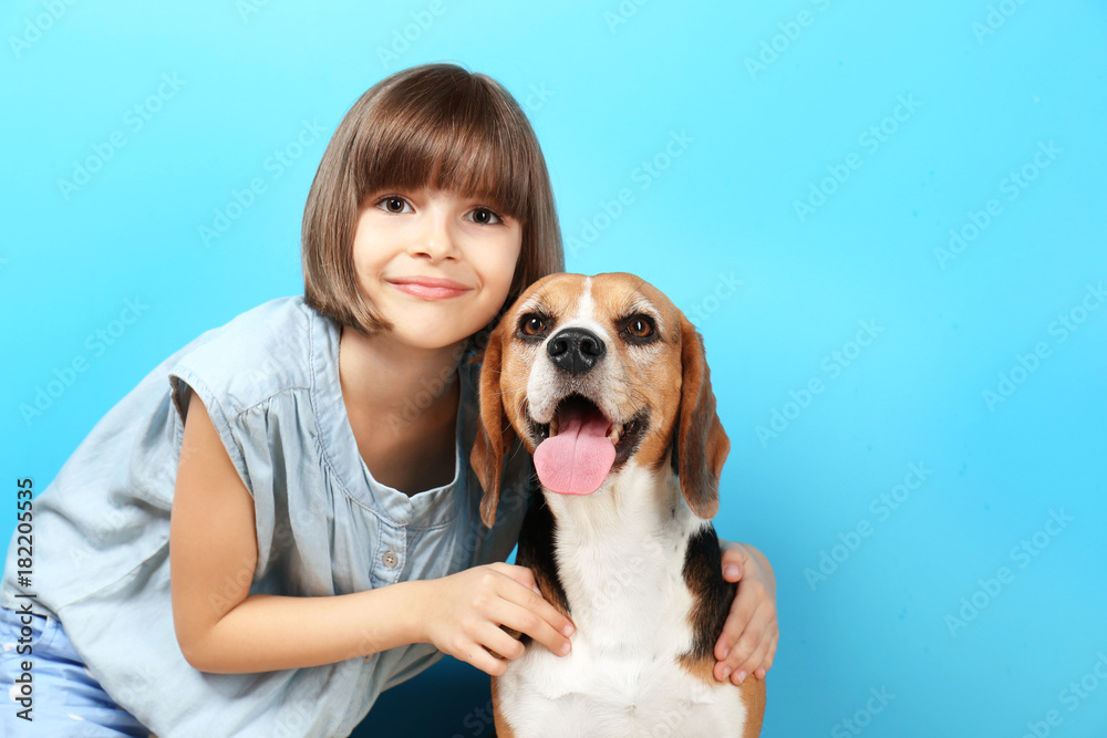 Cute girl with dog on color background