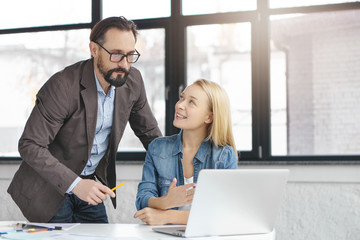 Two cooperative companioship use Internet and modern laptop for searching place to open new office, review all proposals. Female office worker shows results of her work to boss. Business colleagues