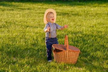 Wall Mural - Toddler child outdoors. One year old baby boy wearing straw hat with picnic basket