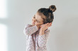 portrait of a little young girl on a white background with a sleepy and happy expression with folded hands to the ear