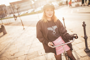 Stylish girl wearing leather hat on her bike on city street