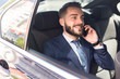 © Seventyfour - Portrait of handsome bearded businessman speaking by phone sitting in back seat of car and smiling happily