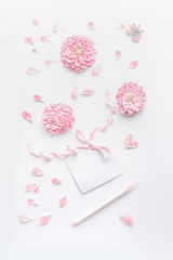 Wall Mural - Pastel color mock up with pink flowers and petals, blank paper card with ribbon and point pen on white desktop background, top view. Layout of greeting card for Mothers day, wedding or happy event