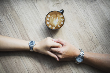 Coffee lover shake hands together with hot latte coffee art on wooden table