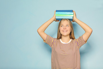 Wall Mural - Cute teenager girl with books on color background